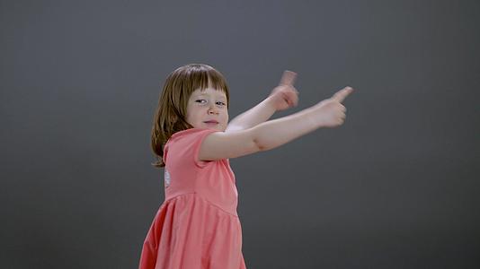 积极的女孩指着灰色背景上的空白空间宝贝酷女孩展示手势视频的预览图