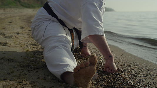 灵活的运动男子在沙滩上伸展特写视频的预览图