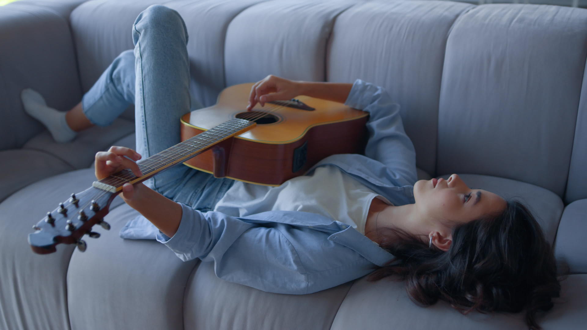 女孩在沙发上弹吉他放松音乐家在吉他上演奏和弦视频的预览图