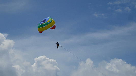 滑翔伞活动丰富多彩的滑翔伞翼和游客在蓝天多云极限运动海滩上视频的预览图