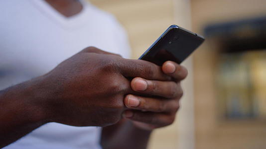 未知的非洲在街上发短信非洲人手里拿着机器视频的预览图
