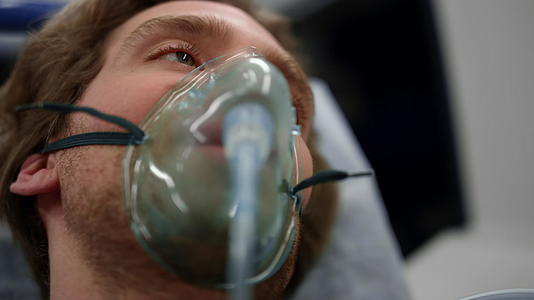 一名戴着氧气面具的受伤男子躺在救护车上的担架上视频的预览图