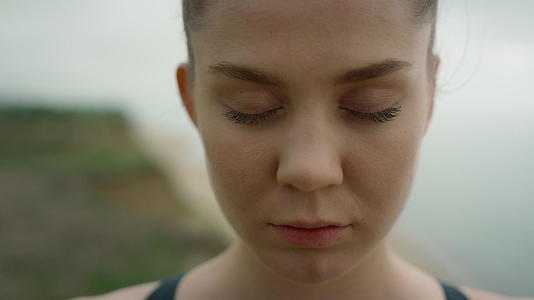 平静的女人睁开眼睛站在沙滩上视频的预览图