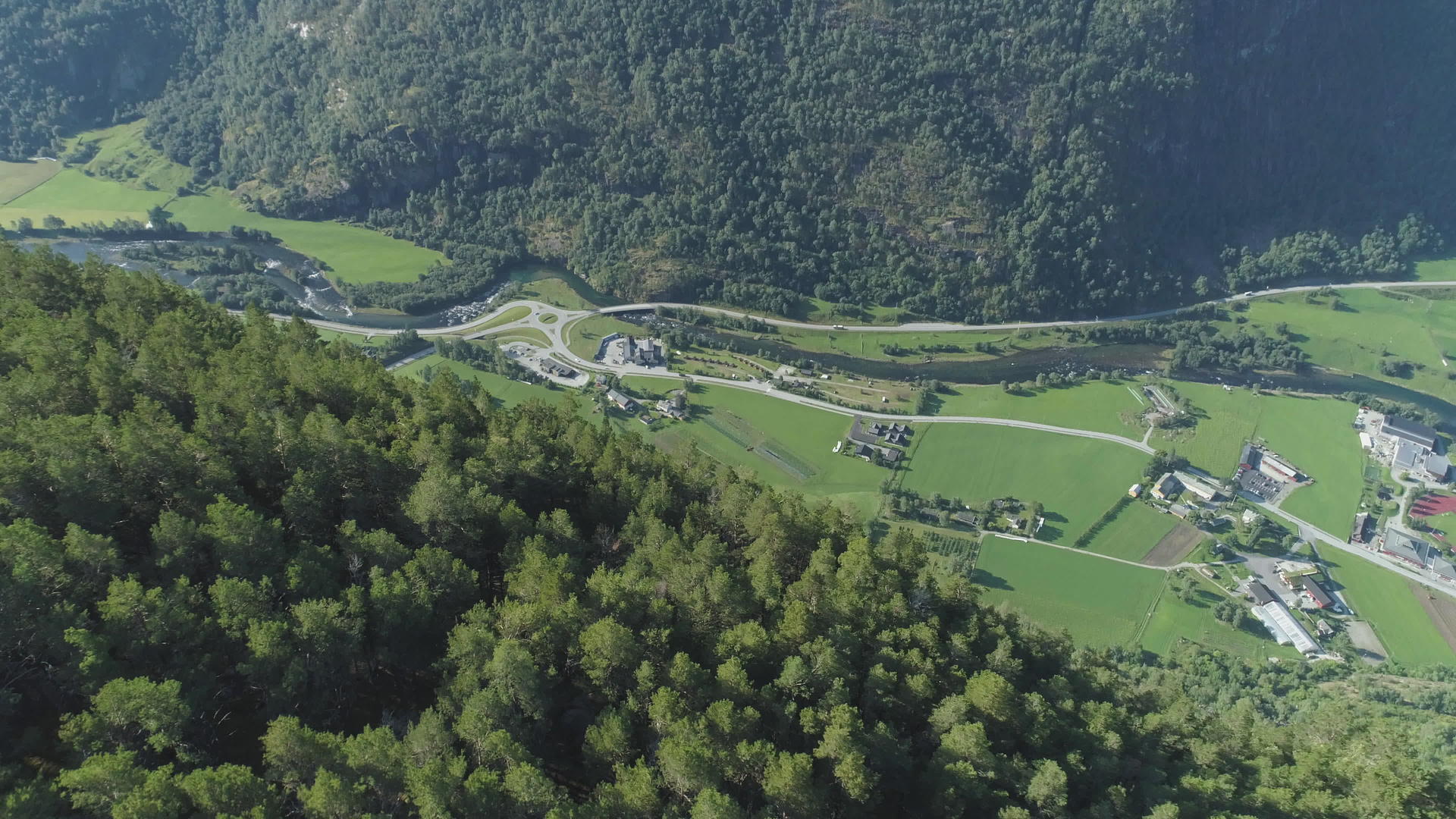 在阳光明媚的夏天挪威的绿树和村庄的山坡在空中展示视频的预览图