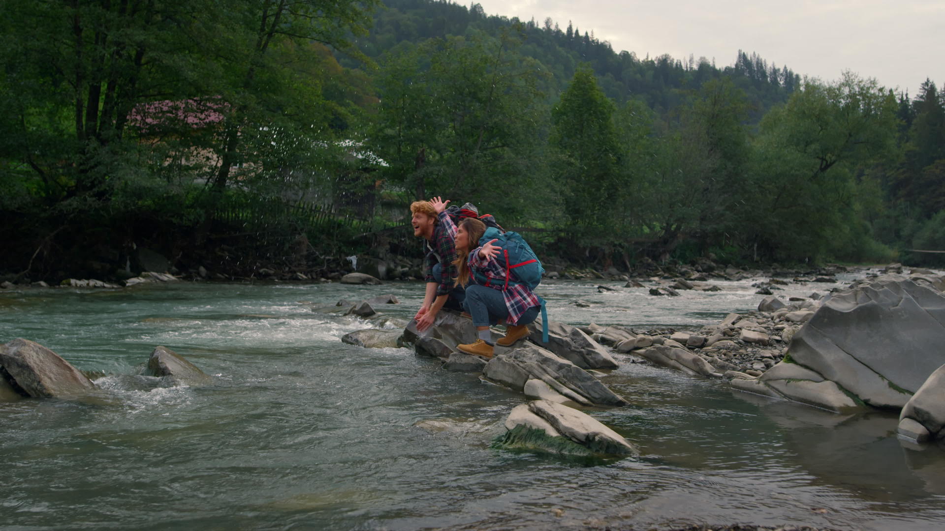 男人和女人坐在河边的岩石上在空中泼水视频的预览图