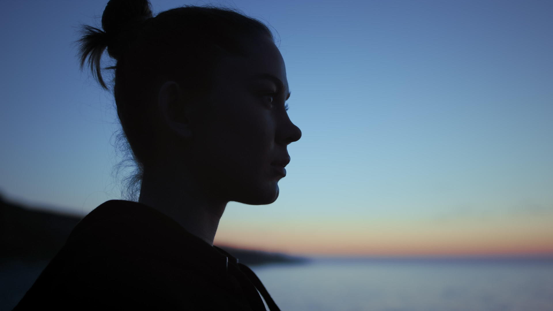 深色剪影脸女人站在前面的傍晚天空视频的预览图
