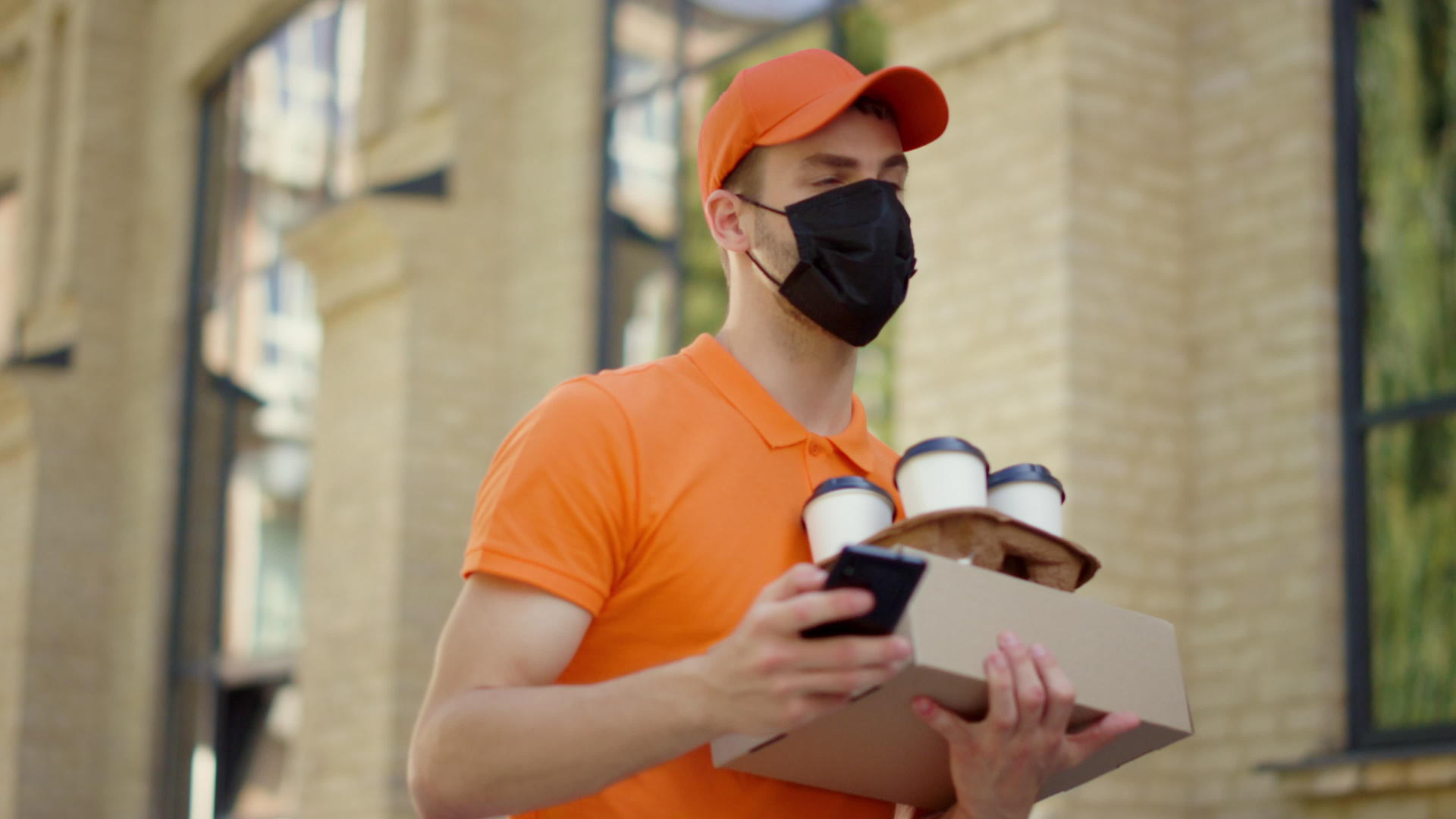 使用智能手机的面具信使送货员在户外订购视频的预览图