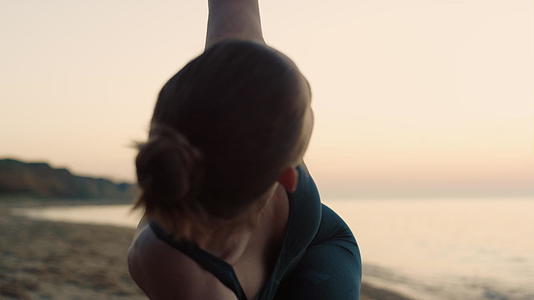 练习三角形姿势的瑜伽女孩在沙滩上视频的预览图