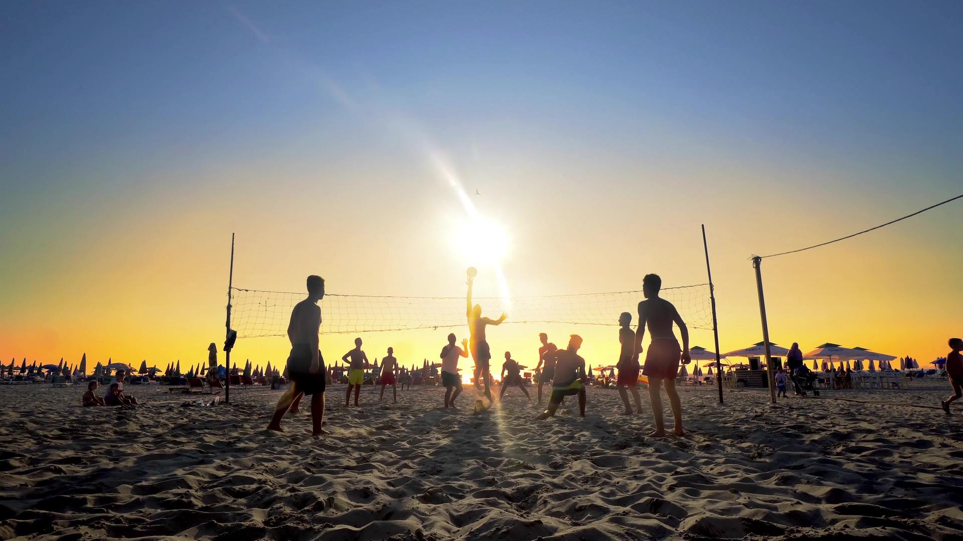 日落时在海滩上打排球的人无法辨认视频的预览图