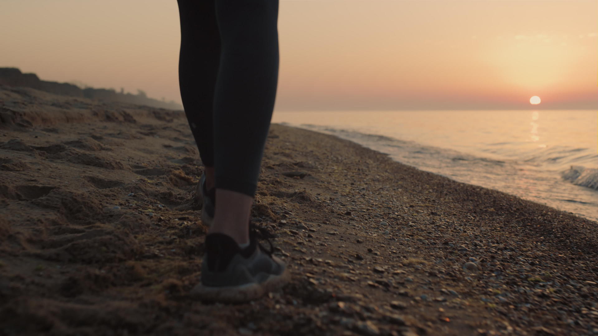 日落时分特写苗条的女人脚走在沙滩上视频的预览图