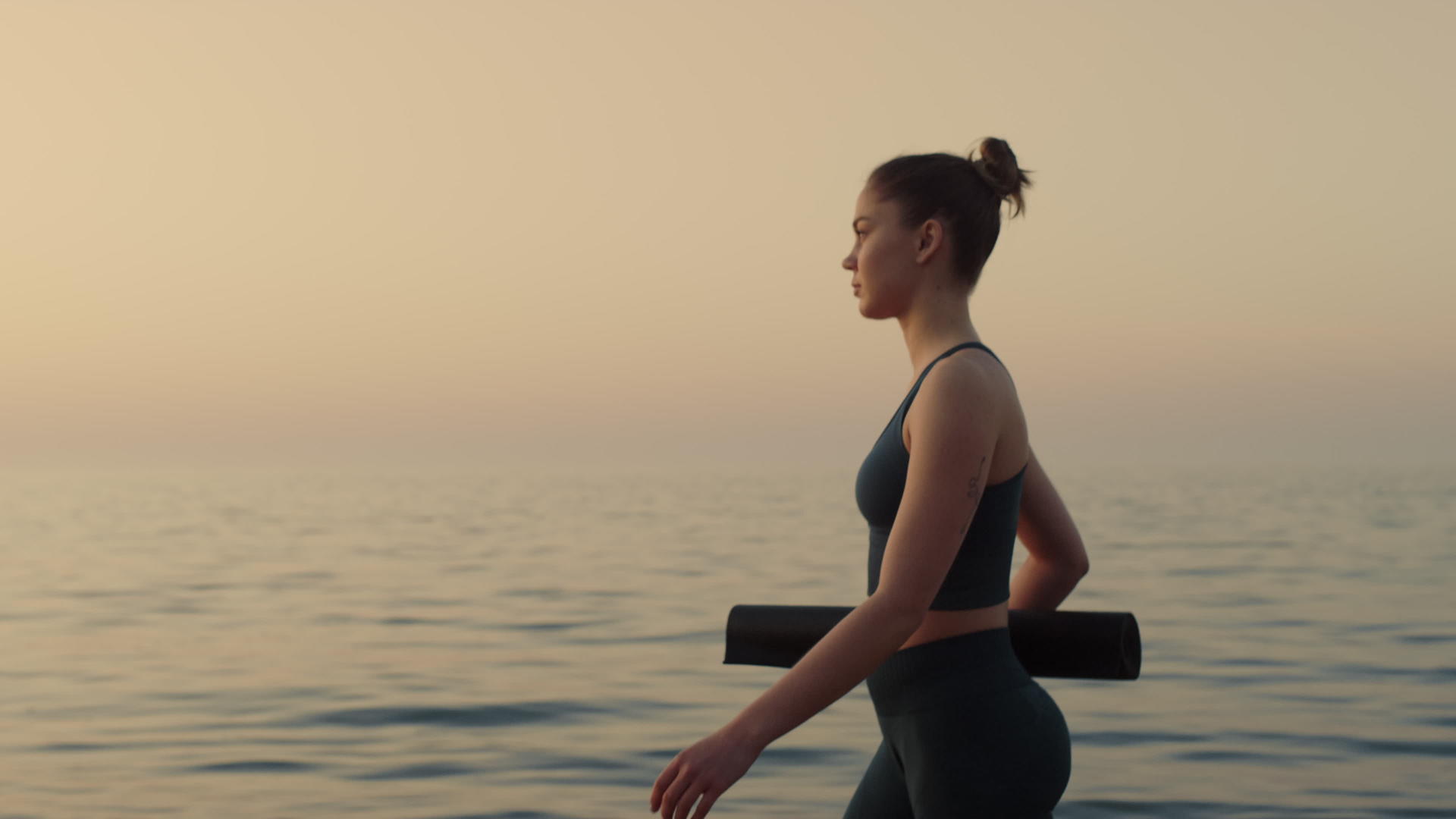 自信的女运动员在日落时分在沙滩上散步视频的预览图