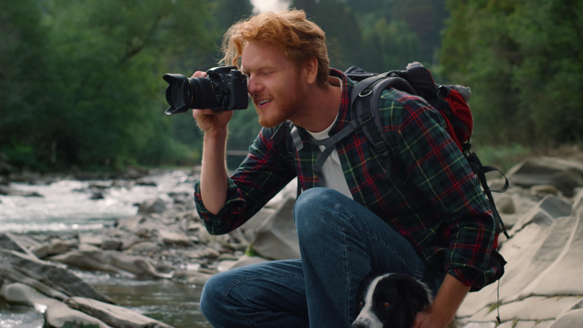 摄影师和狗坐在河岸上视频的预览图