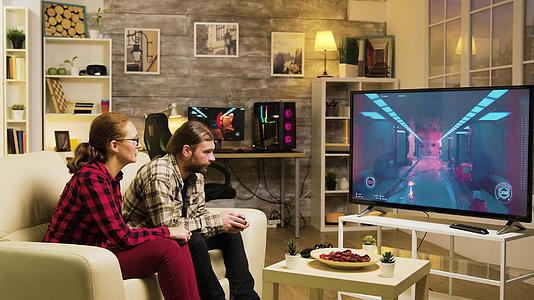 男朋友在玩电子游戏时使用电子游戏TV屏幕上指着女友的女友视频的预览图