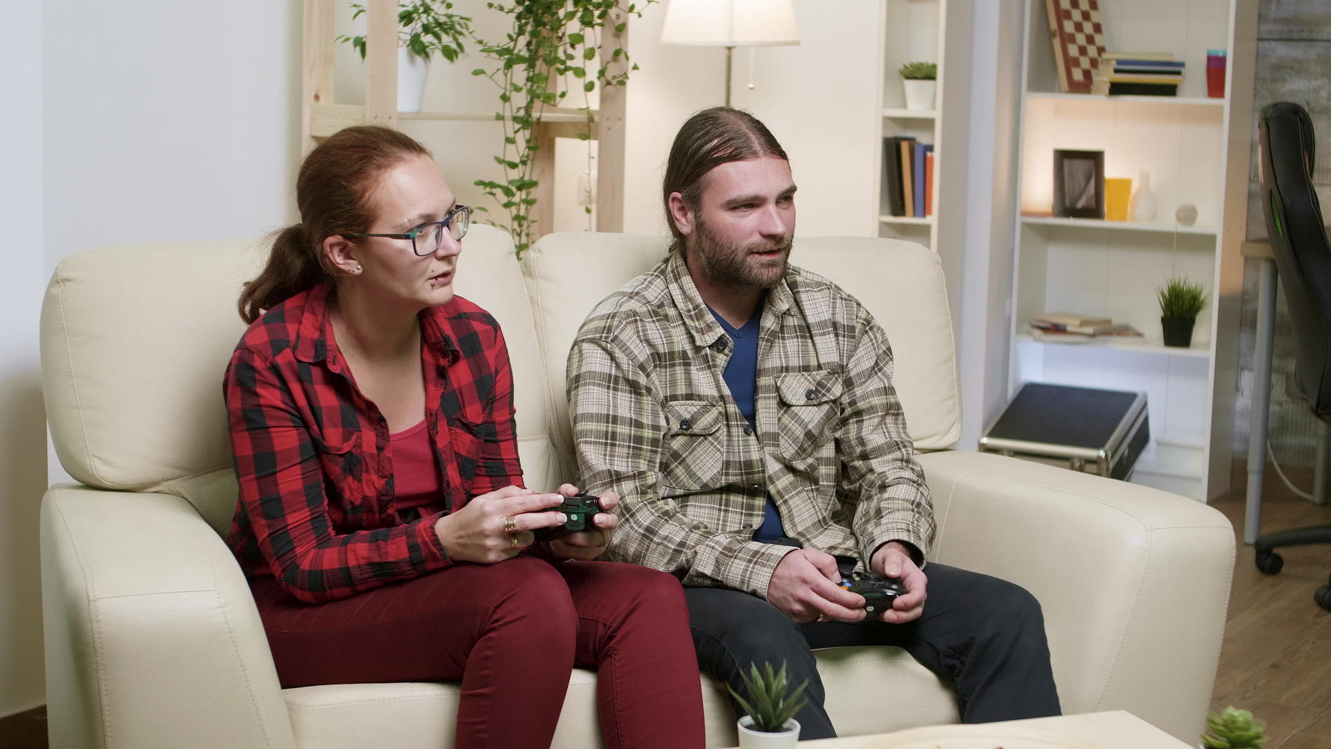 丈夫和妻子坐在沙发上玩电子游戏视频的预览图