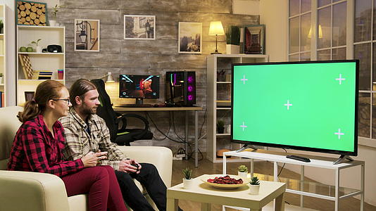 情侣们坐在沙发上玩电子游戏视频的预览图