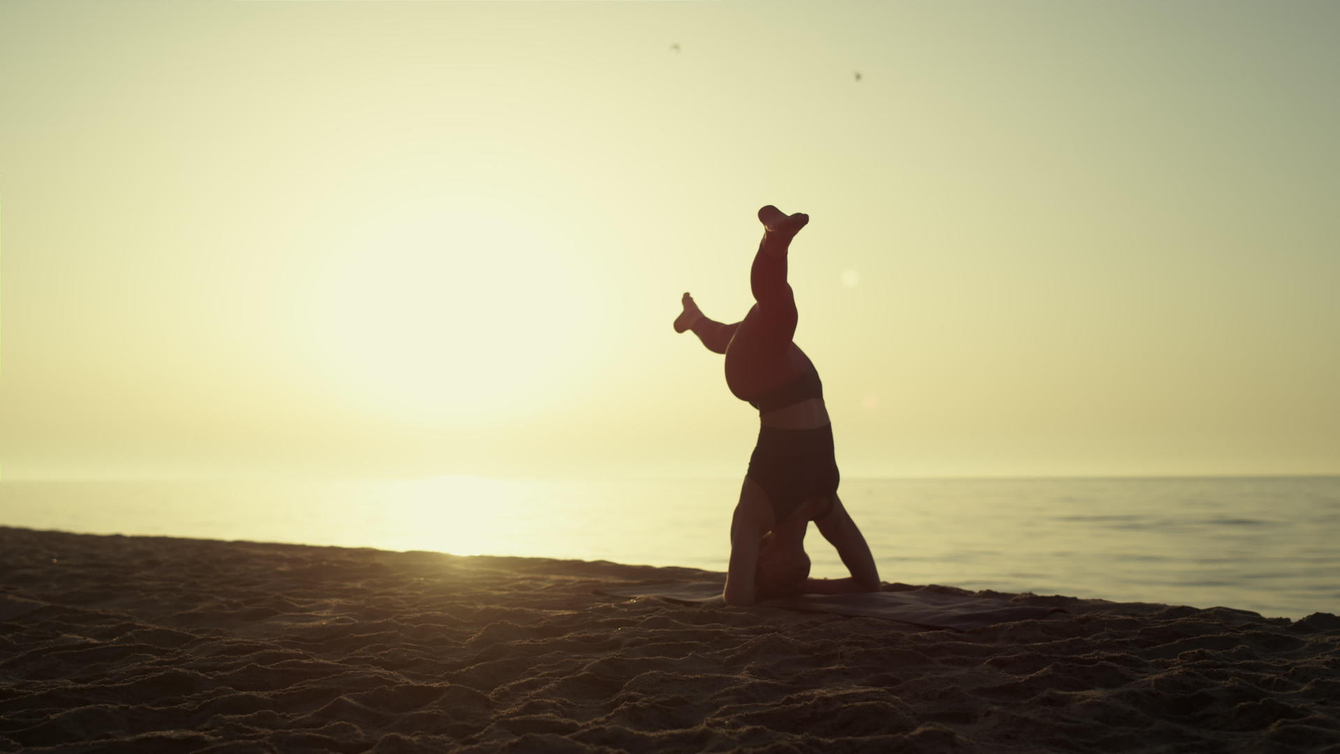 做头倒立的瑜伽妇女正在日落视频的预览图