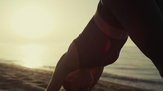 适合女运动员弯曲身体站立瑜伽体式在沙滩上站立视频的预览图