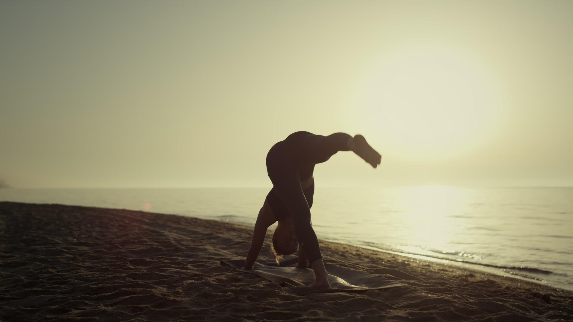 女运动员在日出时练习瑜伽站在沙滩上视频的预览图