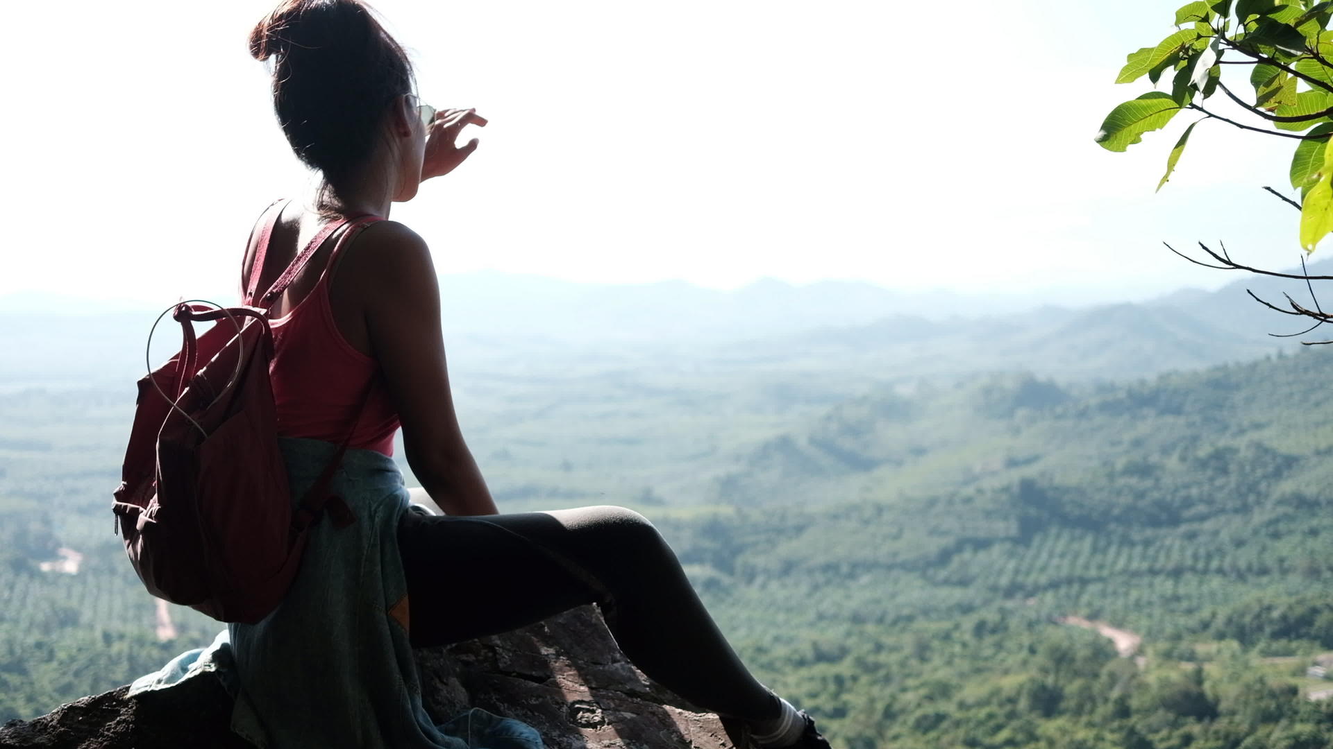 一位年轻女子坐在岩石上在阳光明媚的日子里看着背景视频的预览图