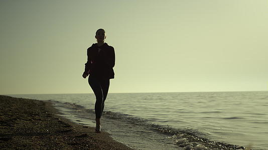 剪影女在日落时分在沙滩上跑步视频的预览图