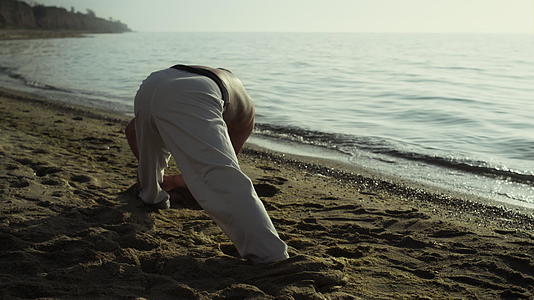 肌肉男在沙滩上伸展身体视频的预览图