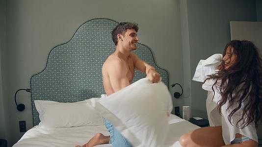 一对幸福的夫妇在床上玩枕头视频的预览图