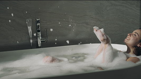 快乐的女孩在浴缸里吹泡泡视频的预览图