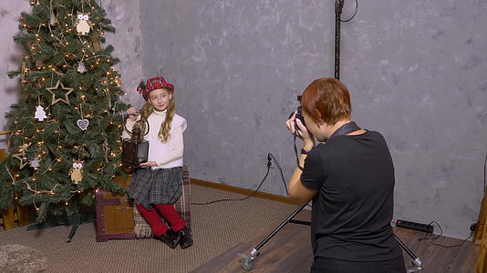 摄影师在圣诞树底背景上拍摄年轻女孩和灯笼视频的预览图