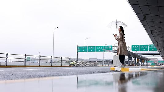 女生撑伞站在路边焦急等车视频的预览图