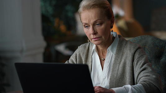 从事膝盖计算机工作的老年妇女看笔记本电脑视频的预览图
