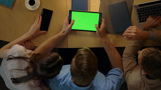 男人和同事一起坐在桌子上企业家们看着绿色的屏幕视频的预览图