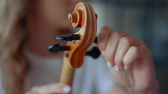 女孩手拉小提琴年轻女子检查小提琴钉子视频的预览图