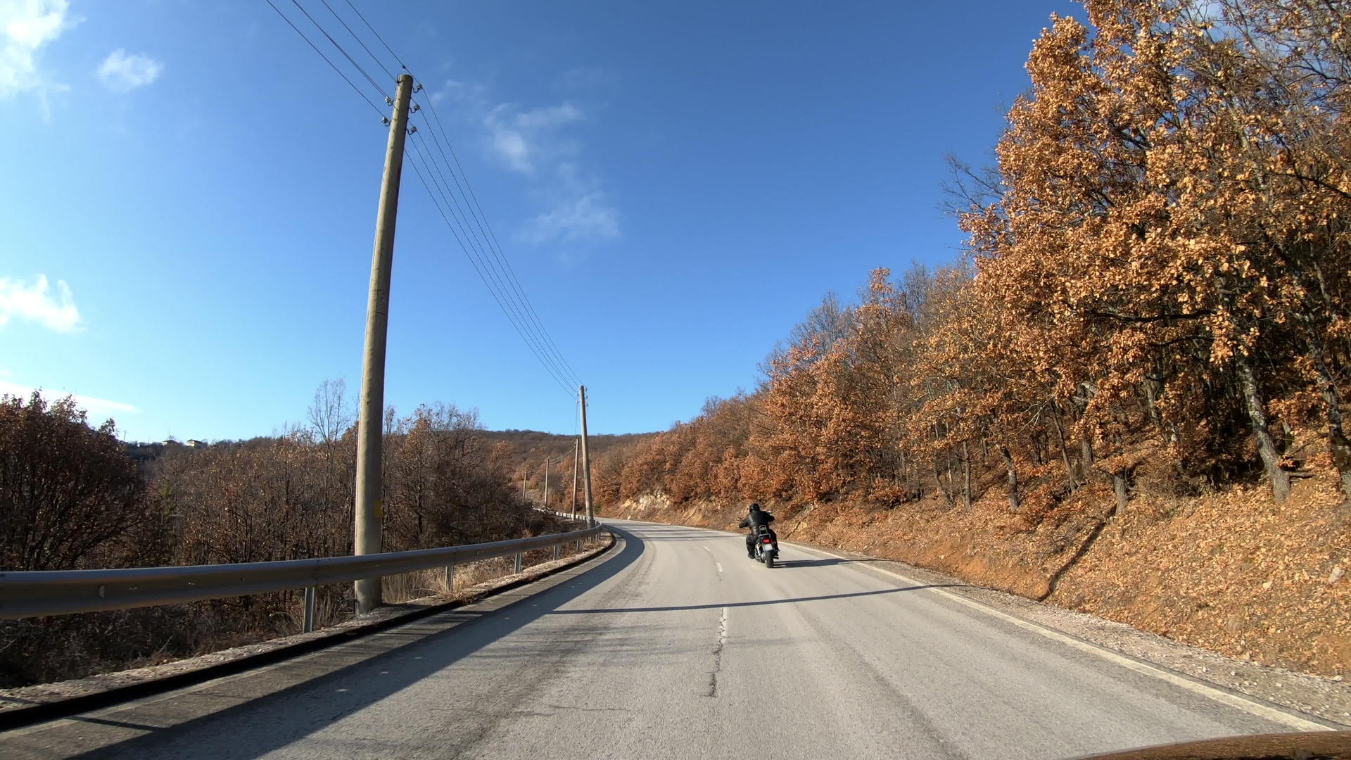 男子骑摩托车在一条开阔的乡村道路上旅行视频的预览图