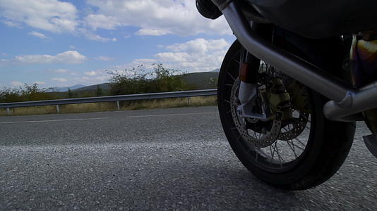 在一条崎岖的沥青路上骑着摩托车在自然道路上行驶视频的预览图