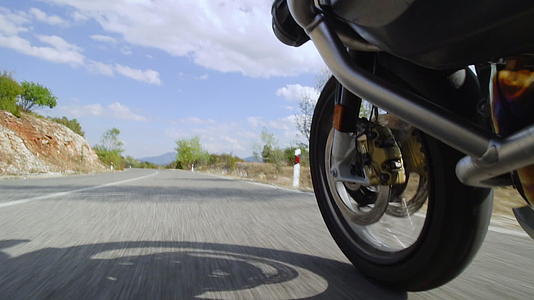 在一条崎岖的沥青路上骑着摩托车在自然道路上行驶视频的预览图