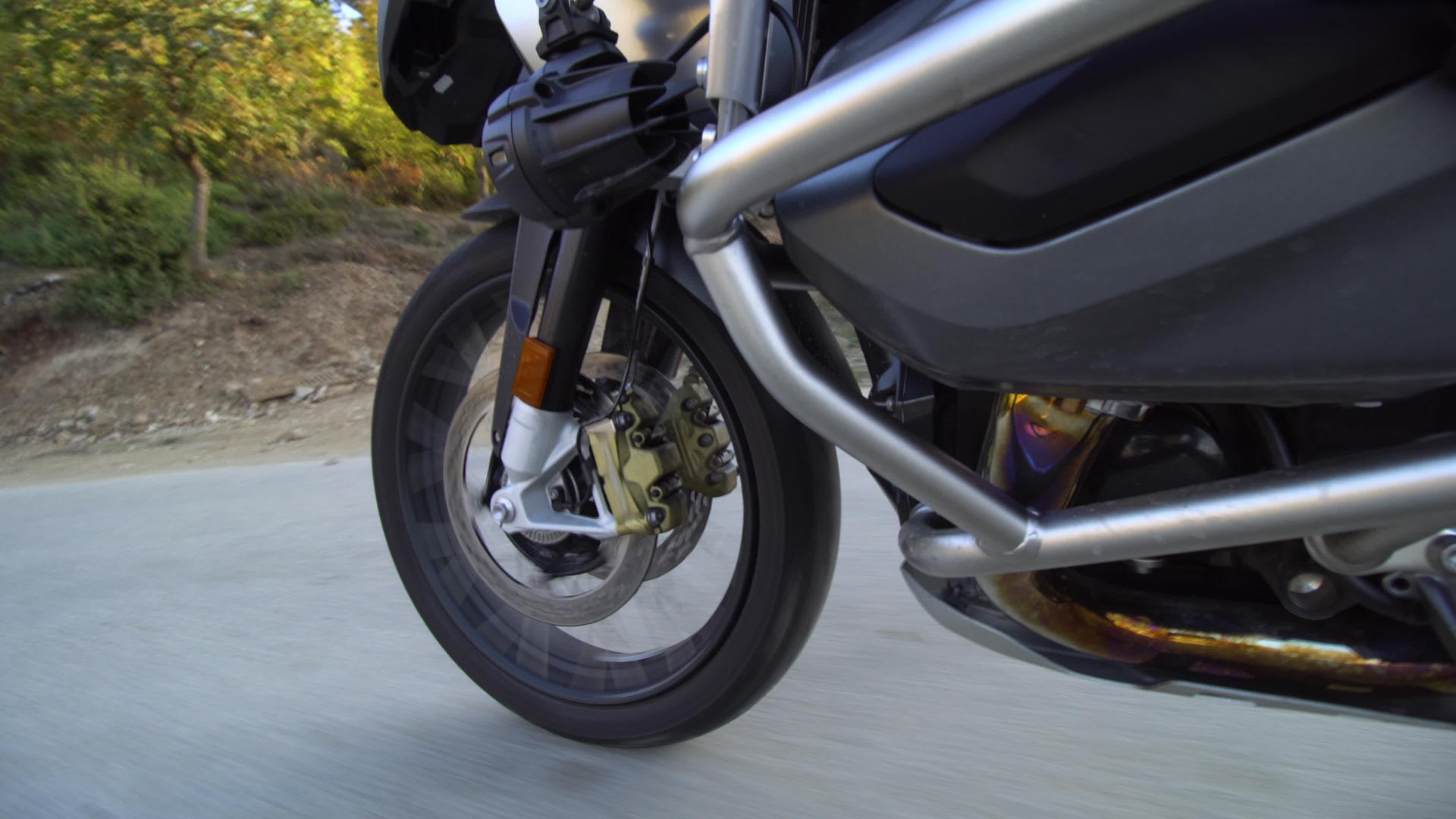 在大自然的道路上骑摩托车在崎岖的柏油路上关闭车轮视频的预览图