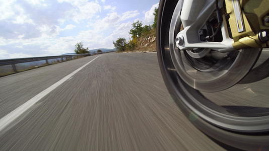 在大自然的道路上骑摩托车在崎岖的柏油路上关闭车轮视频的预览图