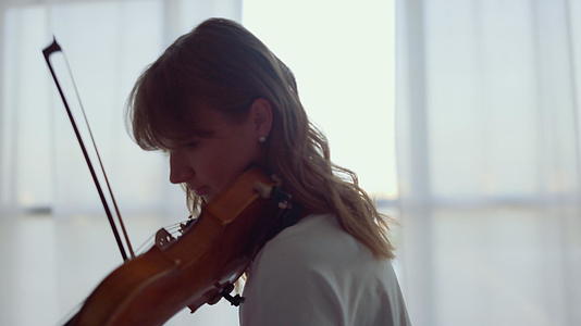 女孩用弓在小提琴上练习音乐粗力主义者在小提琴上演奏和弦视频的预览图