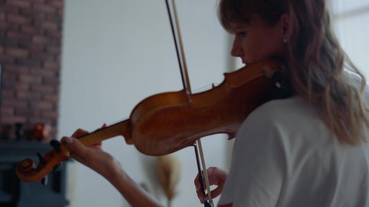 女人在小提琴上演奏音乐迷人的女孩用小提琴弓视频的预览图