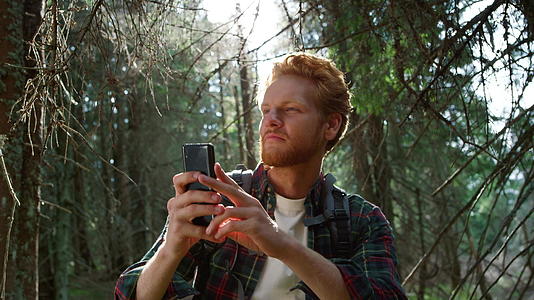 男人在森林里用智能手机拍照视频的预览图