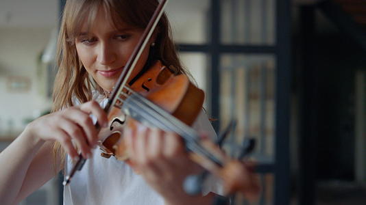 女人在家拉小提琴浪漫的女孩用弓打小提琴视频的预览图