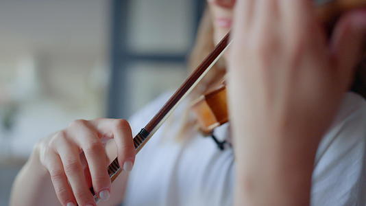 家庭弓琴演奏女孩在弦乐器上创作声音视频的预览图
