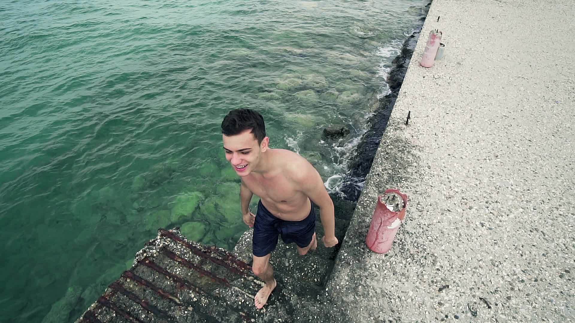 男孩从港口楼梯的海水中出来视频的预览图
