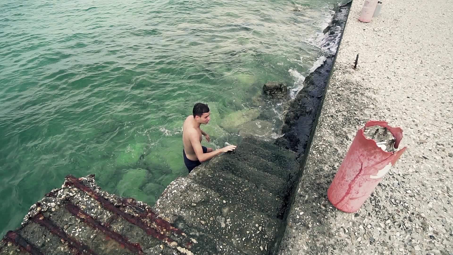 帅帅的运动男孩从港口楼梯的水中慢慢出来慢慢运动视频的预览图