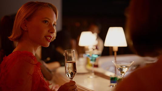 在酒吧喝香槟的漂亮女孩在酒吧和朋友聊天视频的预览图
