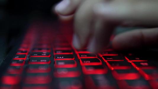 年轻的黑客女孩在黑暗中攻击企业服务器打入红灯笔记本电脑视频的预览图