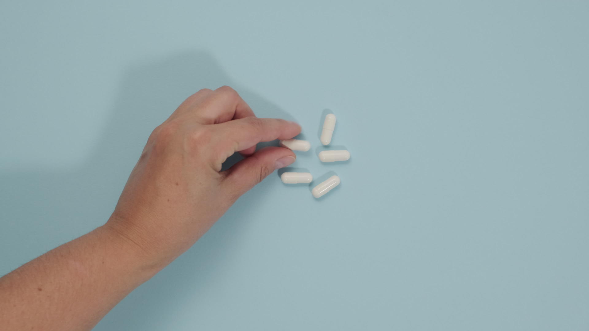 蓝色背景的阴性女性用手折叠奥瓦尔白药片浸泡袋中的药物视频的预览图