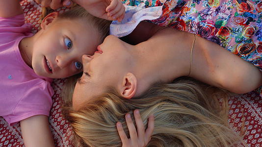 一个女人和一个女孩在花园里用鼻子摩擦母亲和女儿在草地上讲话视频的预览图