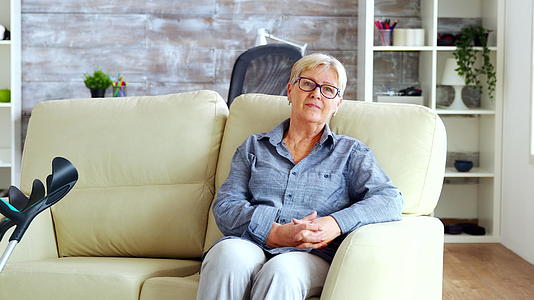 一个孤独的老妇人坐在沙发上的镜头被放大了视频的预览图