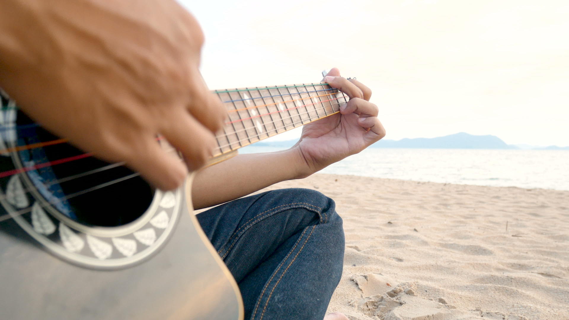4k日落时关闭一个在沙滩上弹吉他的人的近距离感觉视频的预览图